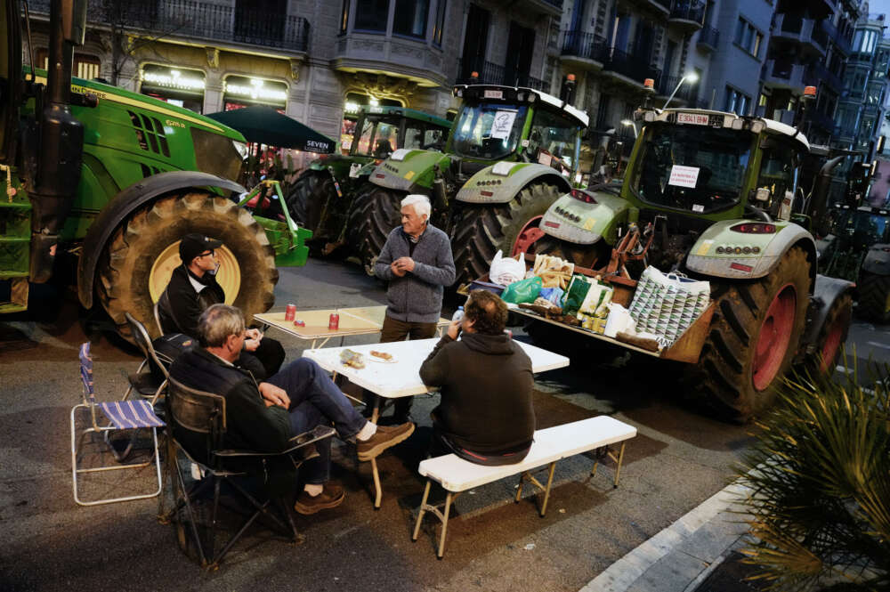 GRAFCAT9485. BARCELONA, 07/02/2024.- Varios agricultores descansan en la calle Argón de Barcelona después de que centenares de tractores hayan tomado el centro de Barcelona durante la marcha agrícola formada por tractores que ha partido de diversos puntos de Cataluña, en una protesta en la que las organizaciones agrarias denuncian el exceso de burocracia, el coste del gasóleo, de los fertilizantes y exigen soluciones urgentes a las administraciones públicas. EFE/Enric Fontcuberta