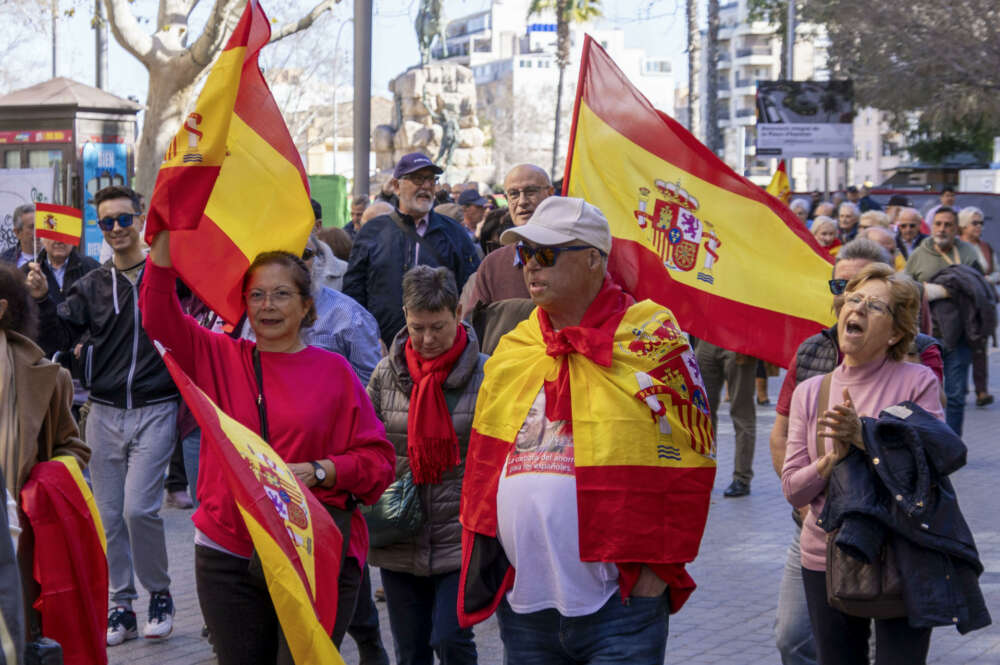 PALMA DE MALLORCA, 18/02/2024.- Manifestantes portan banderas durante protesta convocada este domingo por la Asociación Foro Baleares para pedir la dimisión de Pedro Sánchez y Fernando Grande Marlaska por su gestión tras el asesinato de dos guardias civiles arrollados por una narcolancha. La manifestación partió de la Plaza España hasta la Delegación del Gobierno. EFE/ Cati Cladera