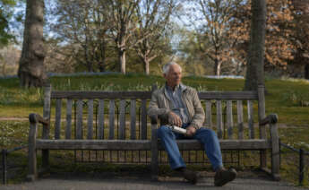 un adulto mayor sentado en una banca de un parque