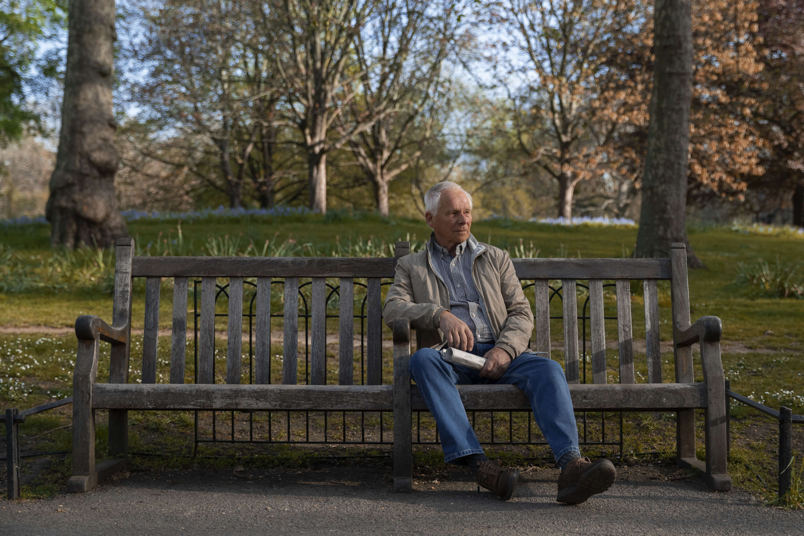 un adulto mayor sentado en una banca de un parque