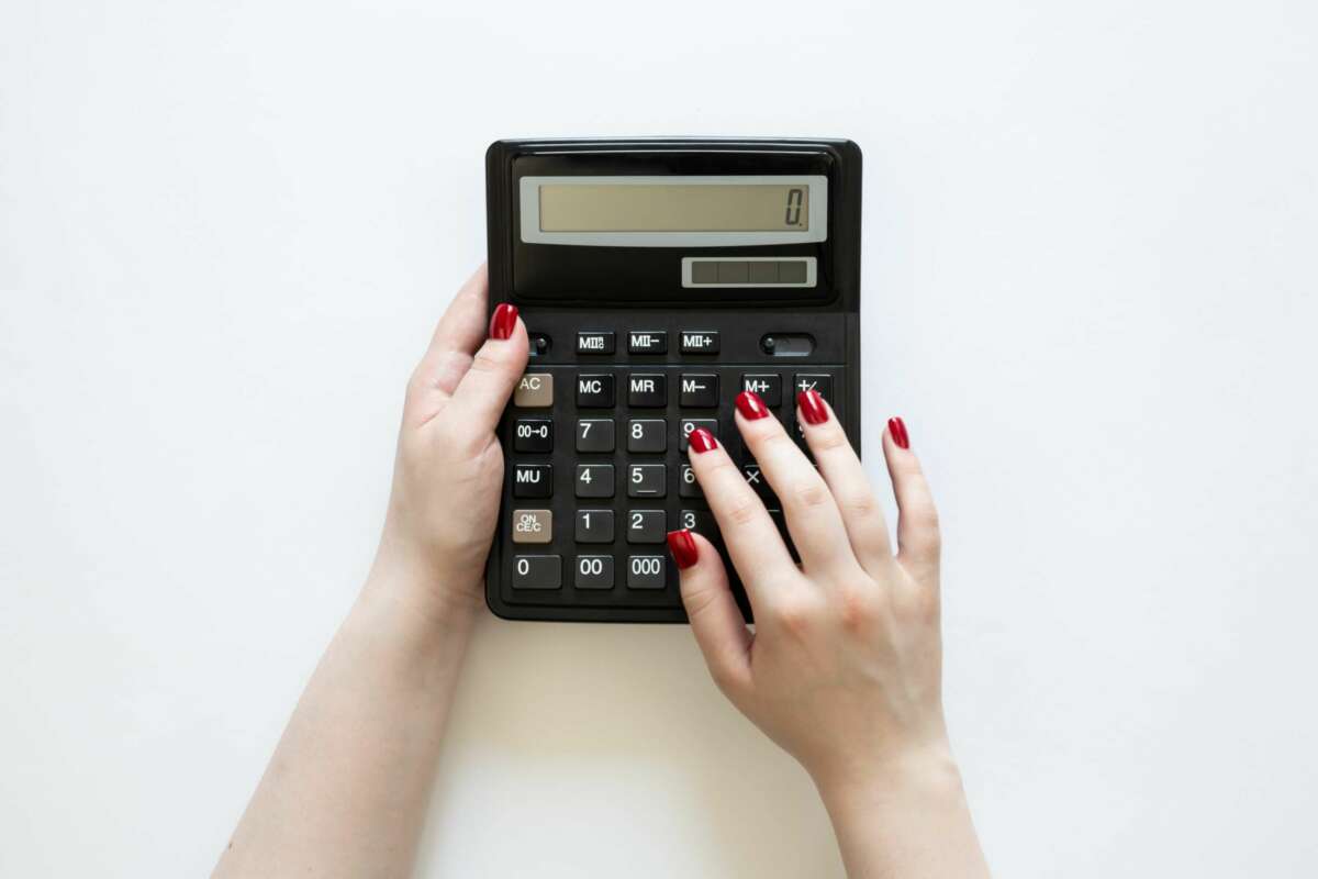 Una mujer realiza un cálculo con una calculadora. Foto: Freepik.