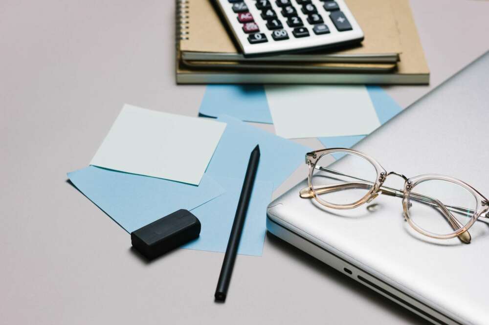 Un escritorio con una calculadora, un portátil y unas gafas. Foto: Freepik.