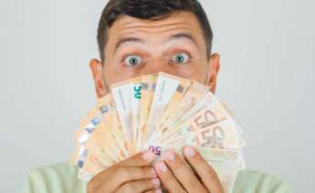 Un hombre sostiene un abanico de billetes de 50 euros tras solicitar un microcrédito. Caixabank. Foto: Freepik.