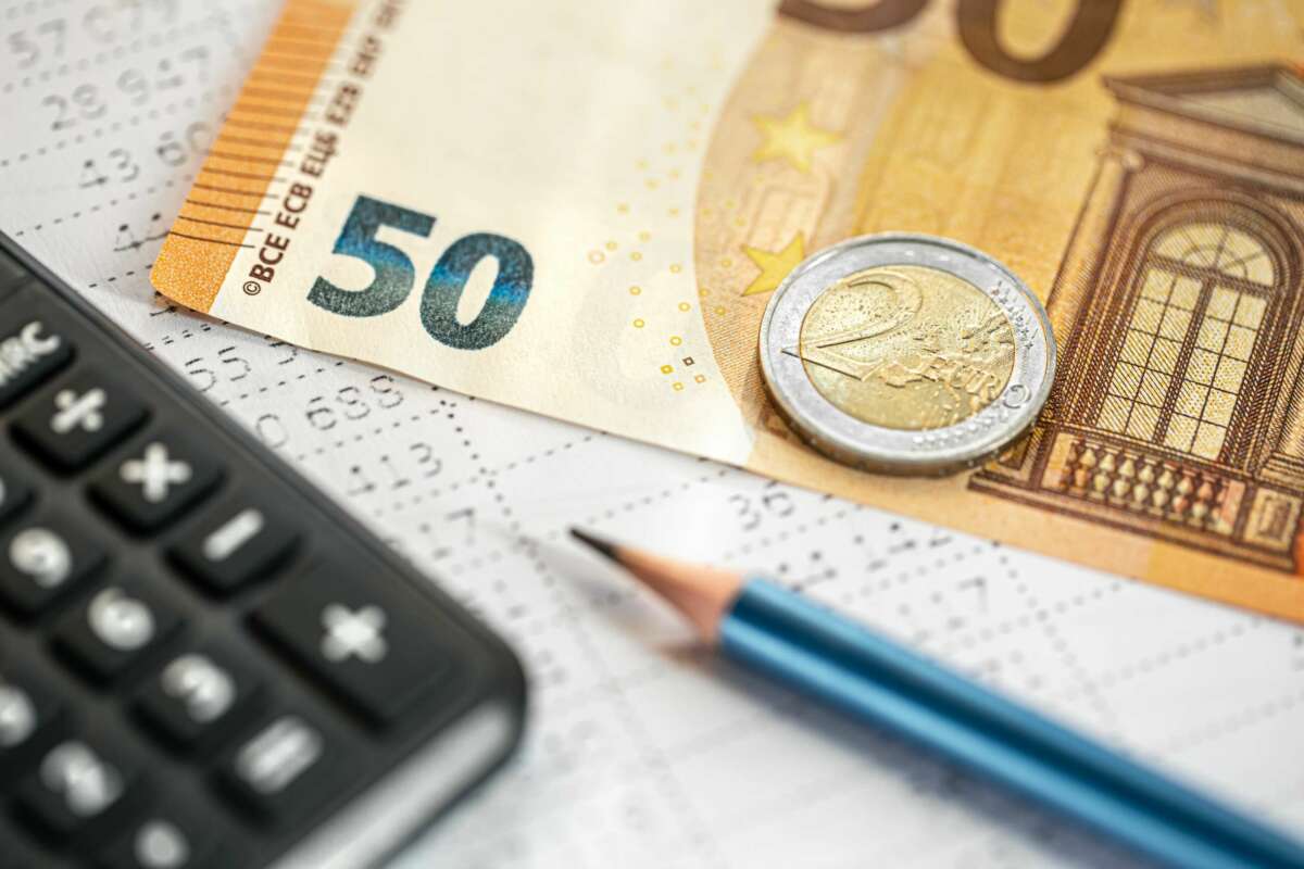 Un billete de 50 euros, una calculadora, un lápiz y una moneda de dos euros. Foto: Freepik.