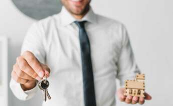 Un hombre sostiene las llaves de una vivienda y una estructura de madera en la otra mano. Foto: Freepik.