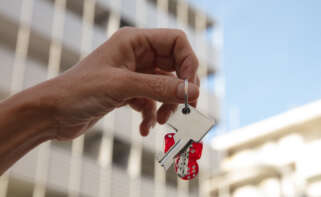 Un hombre sosteniendo llaves detrás de un edificio.