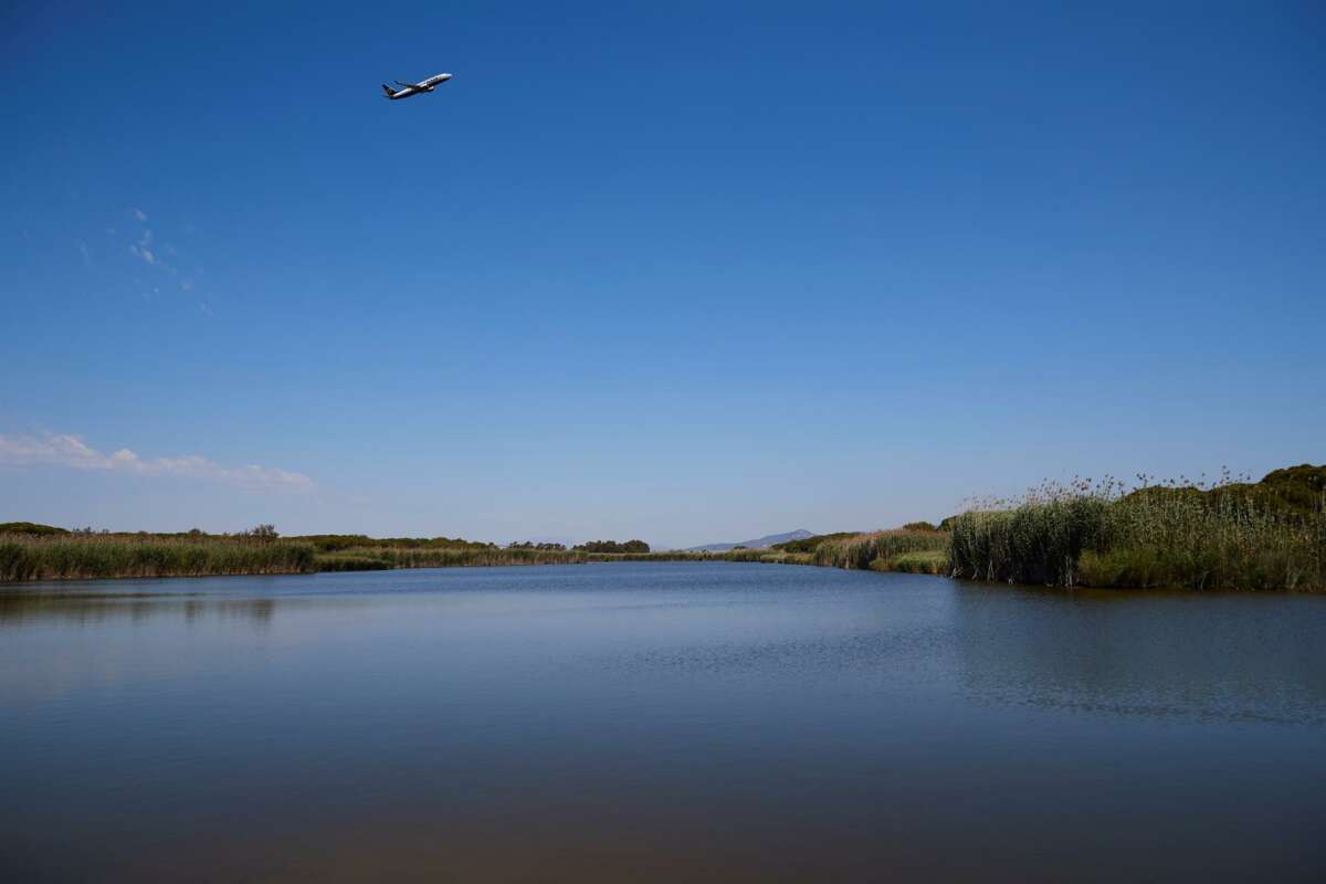 Un avión sobrevuela la zona natural de La Ricarda, que se vería afectada si se amplía la infraestructura. Foto: EFE.