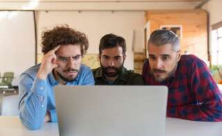 Tres hombres miran con confusión un ordenador. Foto: Freepik.