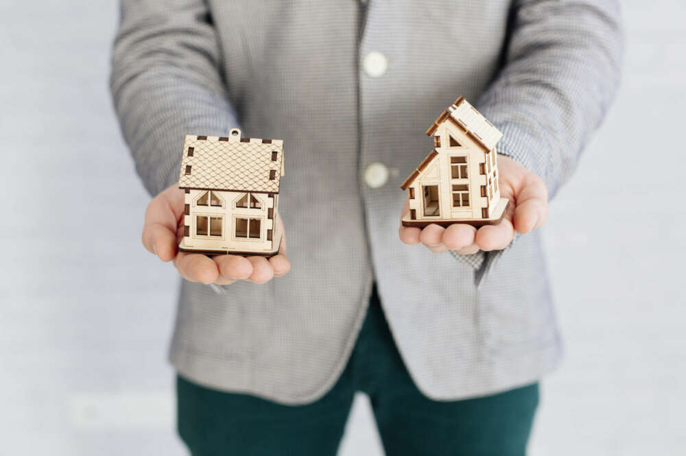 Un hombre sosteniendo dos casas en cada una de sus manos