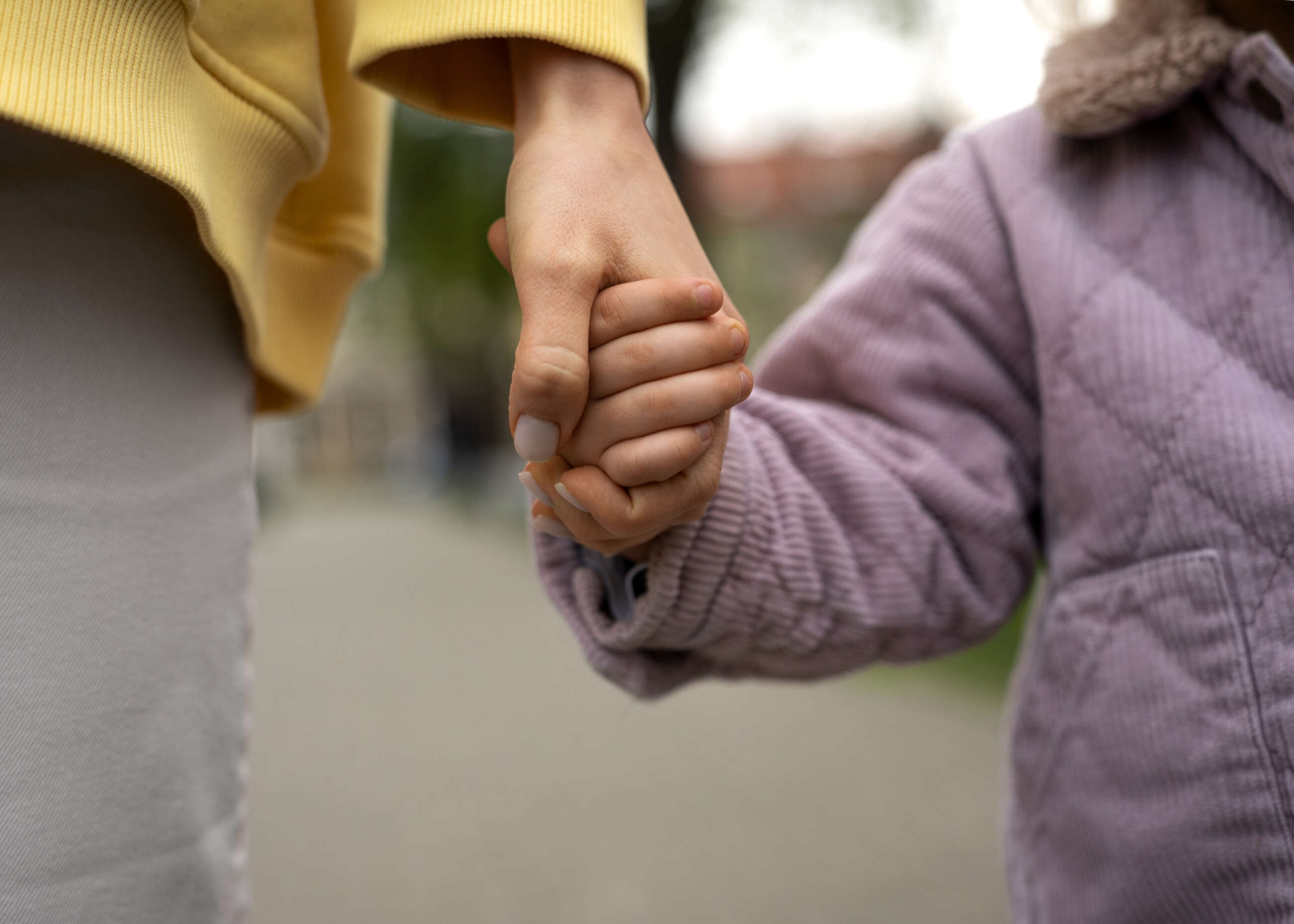 Una mujer sosteniendo la mano de su hija pequeña