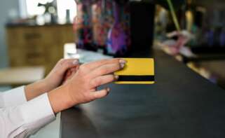 Una mujer paga en un establecimiento con su tarjeta bancaria. Foto: Freepik.
