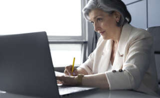 Una mujer realiza un trámite en su ordenador sentada en su escritorio. Foto: Freepik.