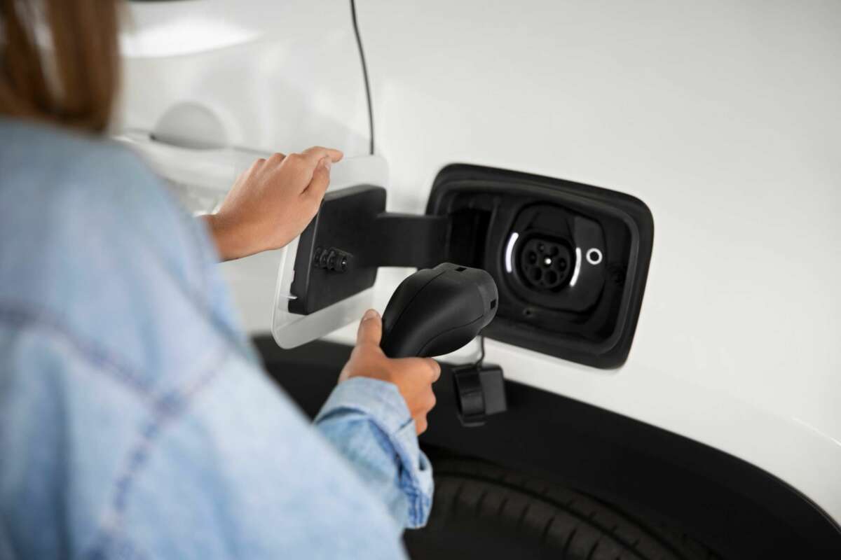 Una consumidora carga el vehículo en la electrolinera. Foto: Freepik.