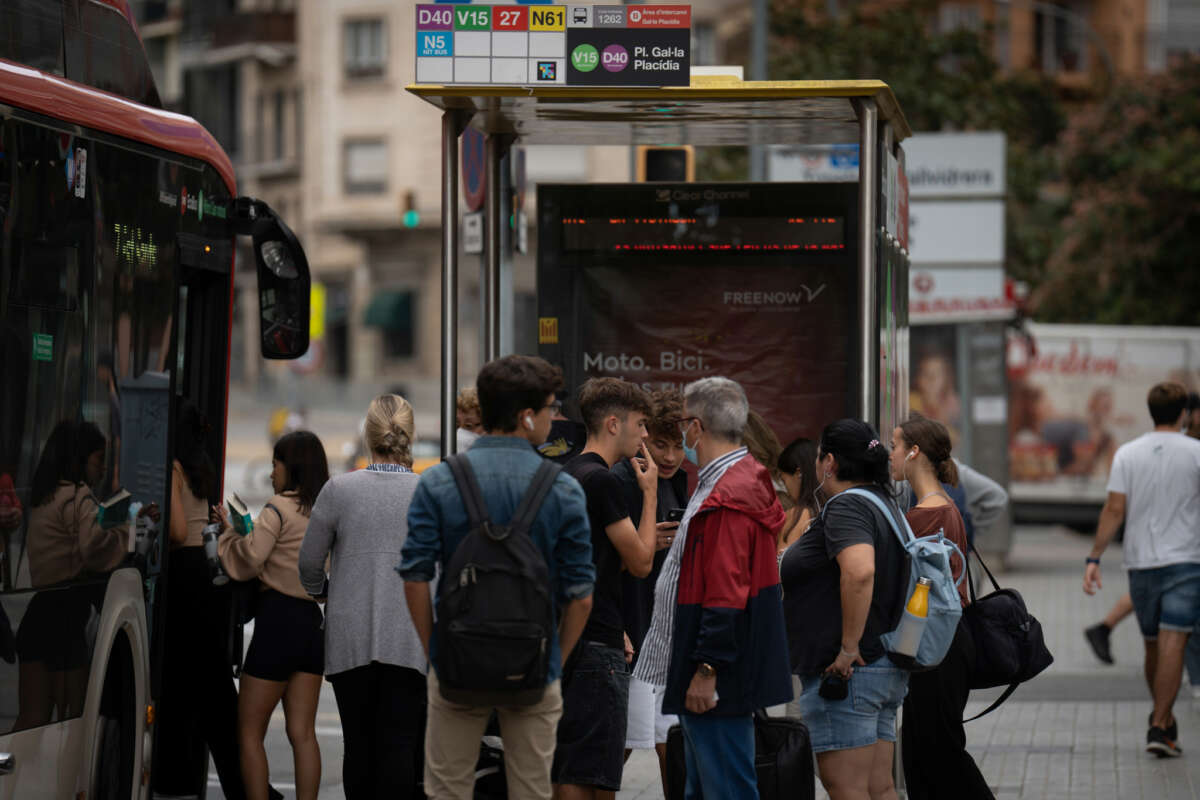 Archivo - Varias personas esperan en la parada de un autobús en Barcelona
