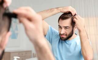 Un hombre observa su cabello frente al espejo