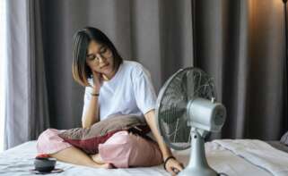 Una chica en su dormitorio con un ventilador