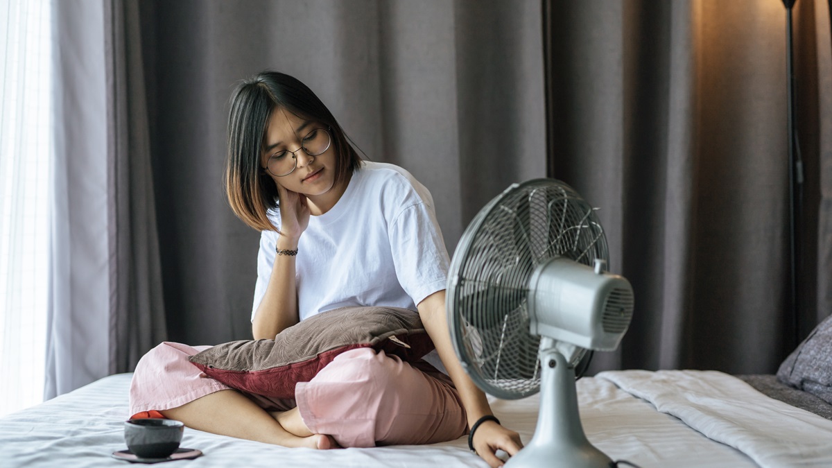 Una chica en su dormitorio con un ventilador