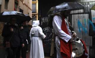Unos cofrades resguardándose de la lluvia