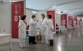 Varios sanitarios conversan este sábado en el punto de vacunación masiva de Valencia situado en la Ciudad de las Artes y las Ciencias. EFE/Biel Aliño