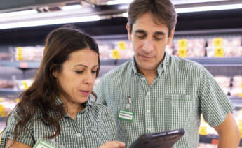 Dos trabajadores de Mercadona miran un dispositivo electrónico.