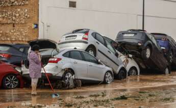 Una mujer realiza labores de limpieza junto a vehículos destrozados tras el paso de la DANA por el barrio de La Torre de Valencia. Foto: Rober Solsona / Europa Press