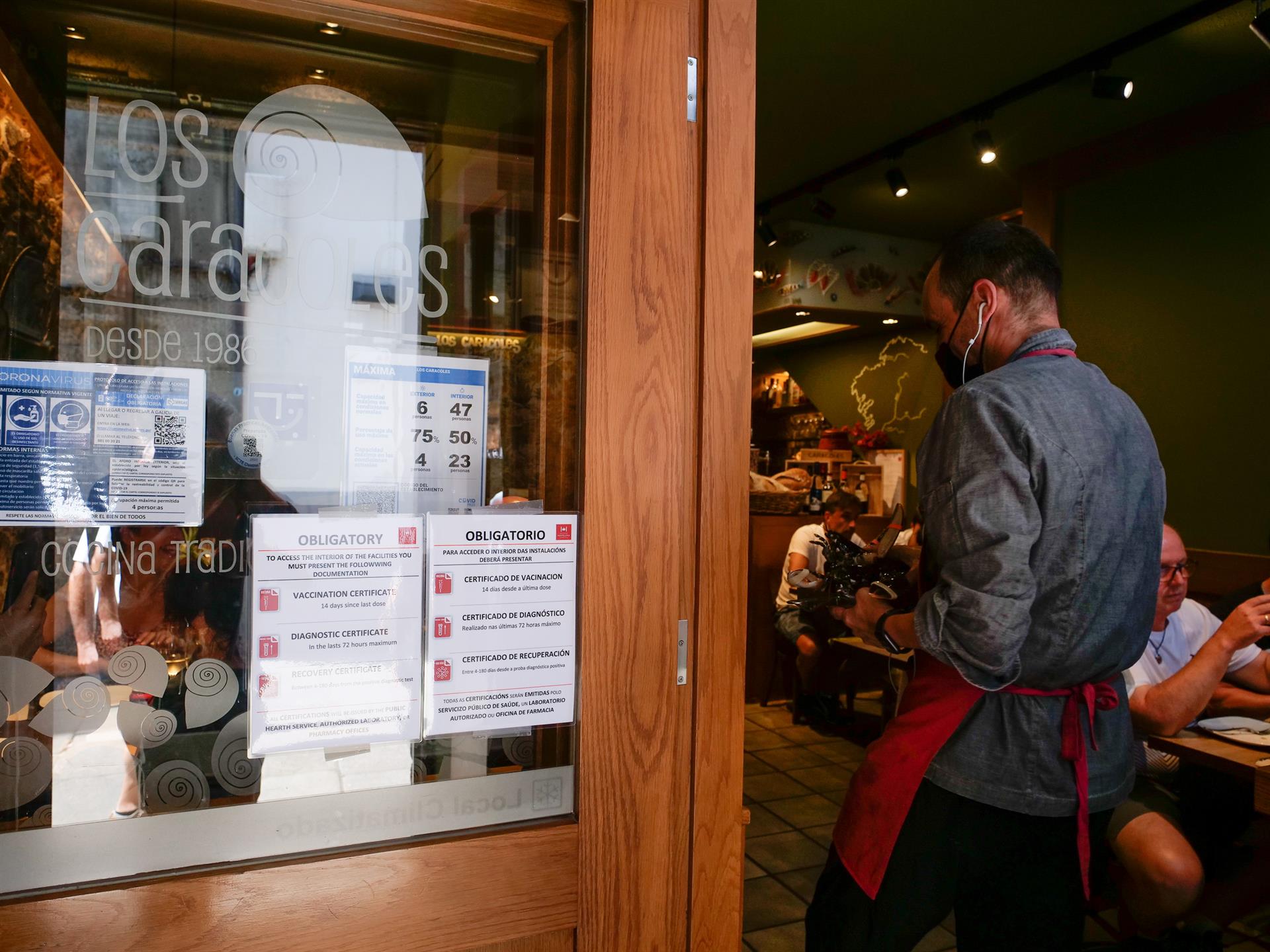 Carteles de indicaciones de obligatoriedad de presentar certificados antes de acceder al interior, en una marisquería de la Rua da Raiña, el día en que el TSXG declara nula la petición de certificado Covid para la hostelería, en Santiago de Compostela - César Arxina