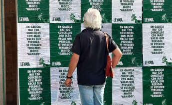 Una persona observa los carteles de la campaña de Leyma