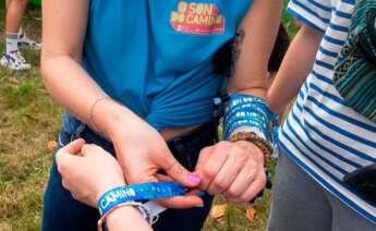 Una chica pone una pulsera en la zona de acampada en el festival Oson de Camiño, en el Monte do Gozo, a 15 de junio de 2022, en Santiago de Compostela