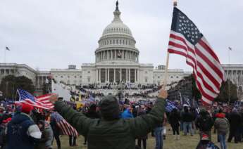Un seguidor de Donald Trump sostiene la bandera de los Estados Unidos frente al Capitolio estadounidense, el 6 de enero de 2021 | EFE/MR/Archivo