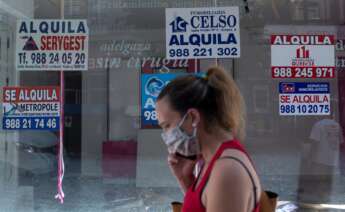 Una mujer con mascarilla pasa ante un comercio cerrado con varios carteles que anuncian su alquiler, el 10 de julio de 2020, en Orense | EFE/BL/Archivo