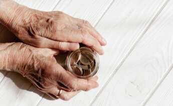 Una anciana coge un frasco con monedas. Foto: Freepik.