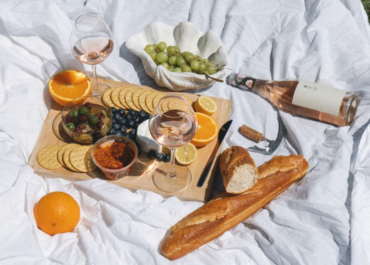 Picnic con copas y botellas de vino, queso y pan